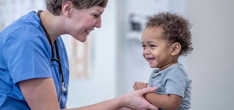 A happy baby laughing during a first vaccination appointment